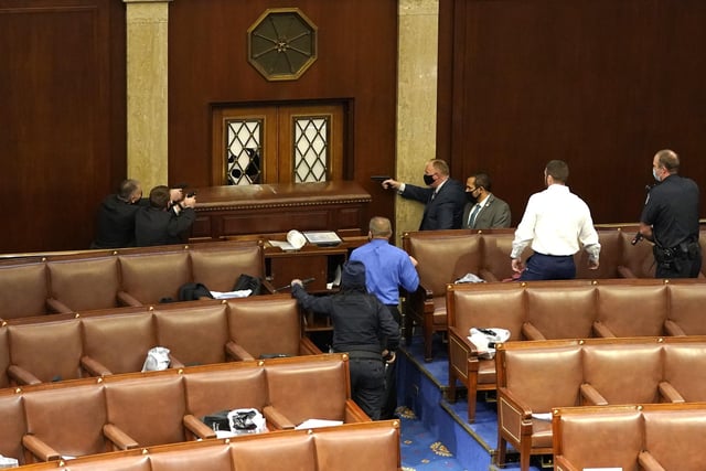 U.S. Capitol police officers point their guns at a door that was vandalized in the House Chamber during a joint session of Congress
