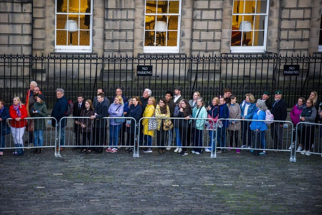 Members of the public stand outside waiting to pay their respects.