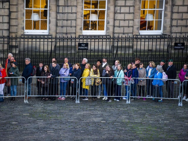 Members of the public stand outside waiting to pay their respects.
