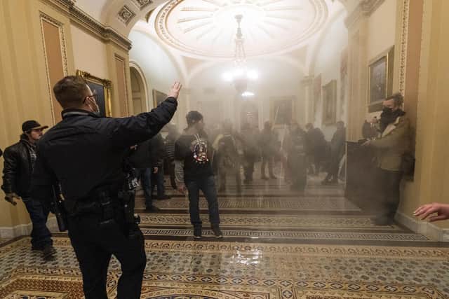 Smoke fills the walkway outside the Senate Chamber as supporters of President Donald Trump are confronted by U.S. Capitol Police officers inside the Capitol