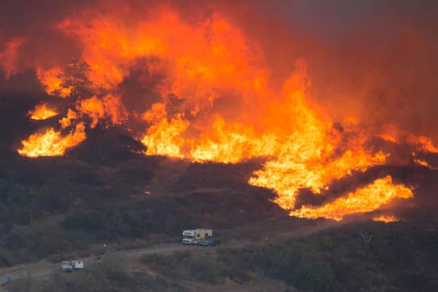 A wildfire closes in on vehicles parked on a country road near Wrightwood, California (Picture: David McNew/Getty Images)