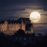 The full moon rises behind Edinburgh Castle.
