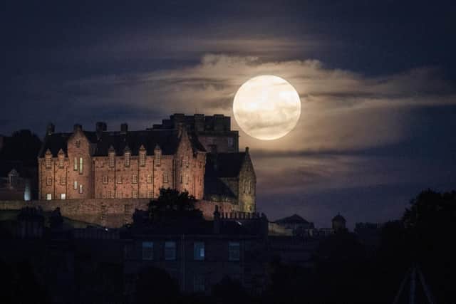 The full moon rises behind Edinburgh Castle.