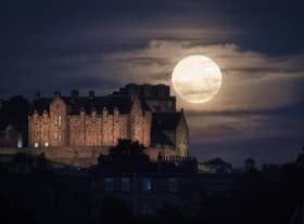 The full moon rises behind Edinburgh Castle.