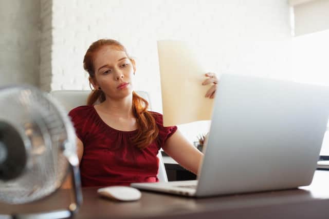 employee working in hot weather with a fan on desk