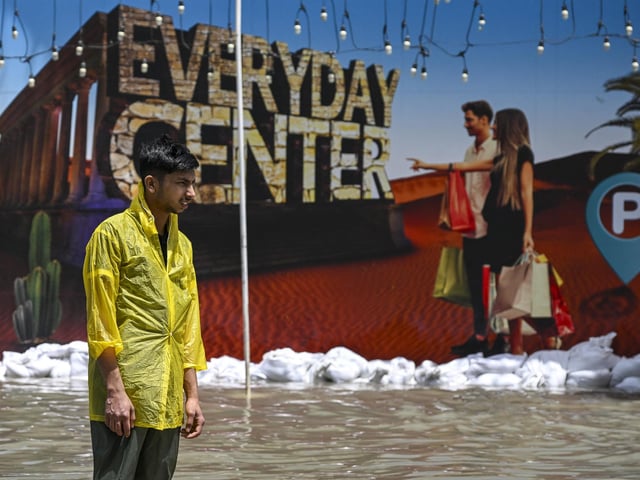 A man stands in a flooded street following heavy rains in Sharjah, UAE.