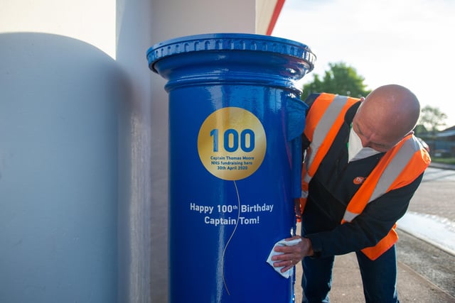 A man polishes a letter box painted blue to mark the 100th birthday of Second World War veteran Captain Tom Moore close to the home in Marston Moretaine, near Bedford.