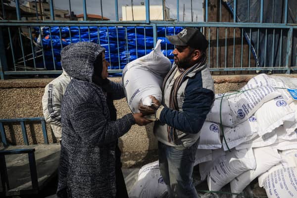 Displaced Palestinians receive food aid at the United Nations Relief and Works Agency for Palestine Refugees (UNRWA) center in Rafah in the southern Gaza Strip (Photo by -/AFP via Getty Images)