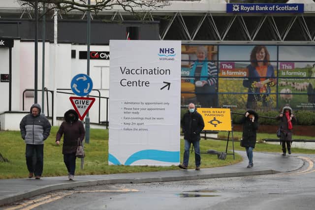 People walk passed a Vaccination Centre sign at the Royal Highland Show ground in Edinburgh in February.
