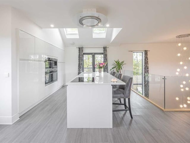 Kitchen with granite worktops, gloss white floor to ceiling units, integrated appliances, and a central island with sink and induction hob.