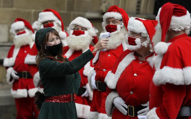 Santas have their temperature taken as they attend a socially distanced Santa school training at Southwark Cathedral in London