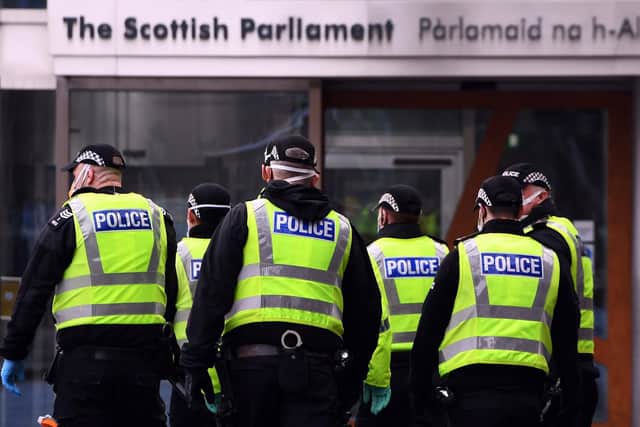 Police officers stand outside the Scottish Parliament as members of the public attend an anti lockdown protest held by The Scotland Against Lockdown group in Edinburgh. Picture: Andy Buchanan/AFP via Getty Images