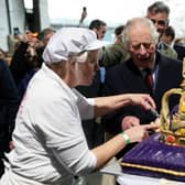 King Charles is helped by an employee to cut a cake in the shape of a crown during his state visit to Germany last month (Picture: Jens Büttner/pool/AFP via Getty Images)