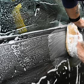 A black car being washed with soap and a sponge