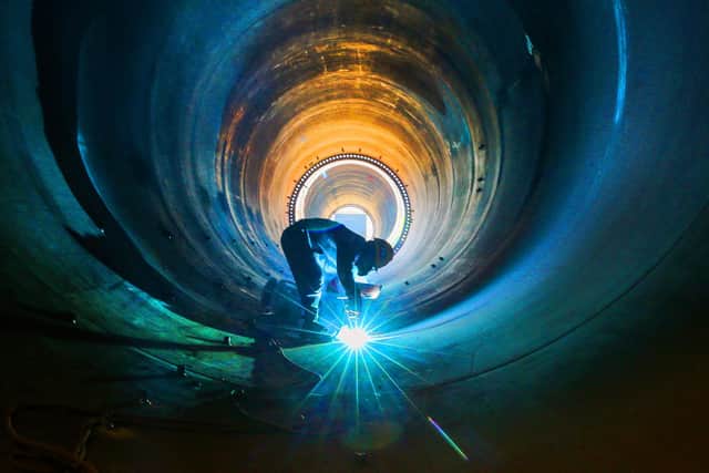 An employee works on a wind turbine tower at a factory in Lianyungang, in China's eastern Jiangsu province (Picture: STR/AFP via Getty Images)