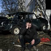 A man sits outside his destroyed building after bombings on the eastern Ukraine town of Chuguiv on February 24, 2022