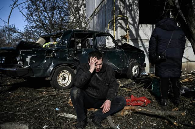 A man sits outside his destroyed building after bombings on the eastern Ukraine town of Chuguiv on February 24, 2022