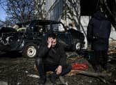 A man sits outside his destroyed building after bombings on the eastern Ukraine town of Chuguiv on February 24, 2022
