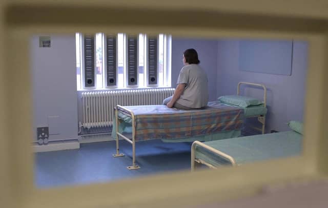 A woman prisoner sits alone in a prison health wing.