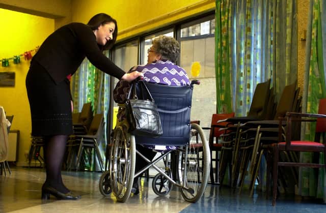 Nurse in a care home talking to an elderly woman in a wheelchair