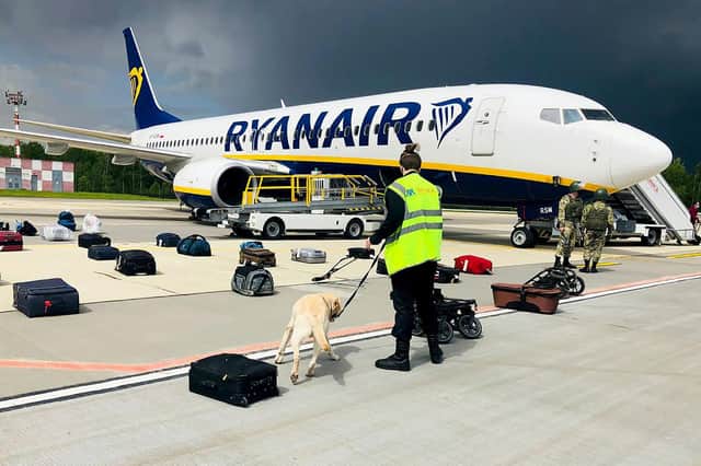 A Belarusian dog handler checks luggages off a Ryanair Boeing 737-8AS (flight number FR4978) parked on Minsk International Airport's apron in Minsk