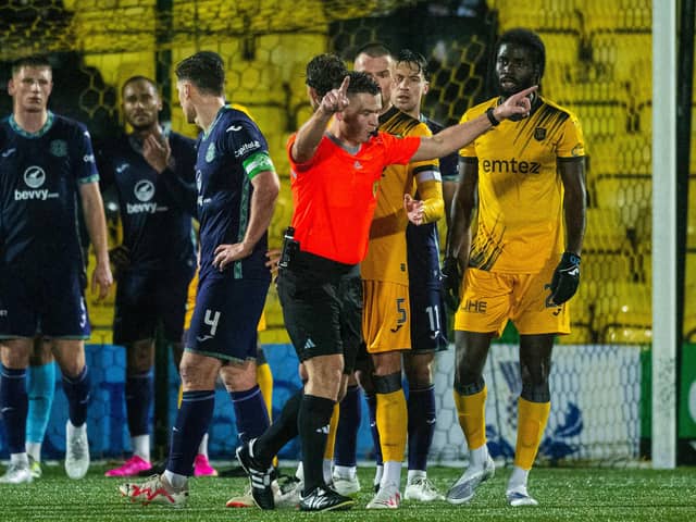 Referee Grant Irvine checks VAR during the match between Livingston and Hibs.