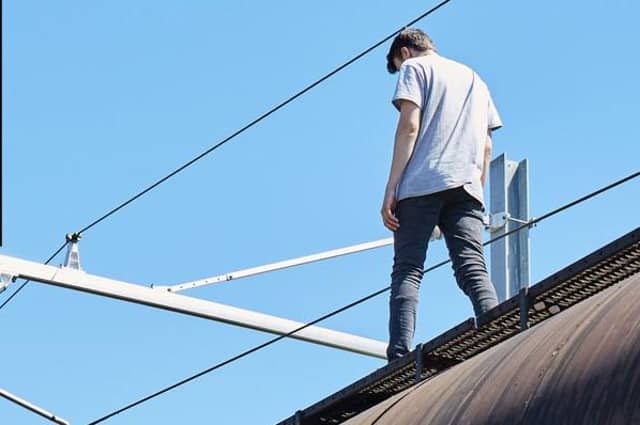 A youth on top of a train beneath 25,000-volt power cables in a Network Rail safety video. (Picture: Network Rail)