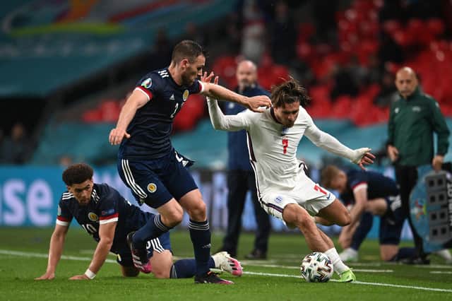LONDON, ENGLAND - JUNE 18: Jack Grealish of England runs with the ball whilst under pressure from Stephen O'Donnell and Che Adams of Scotland during the UEFA Euro 2020 Championship Group D match between England and Scotland at Wembley Stadium on June 18, 2021 in London, England. (Photo by Andy Rain - Pool/Getty Images)