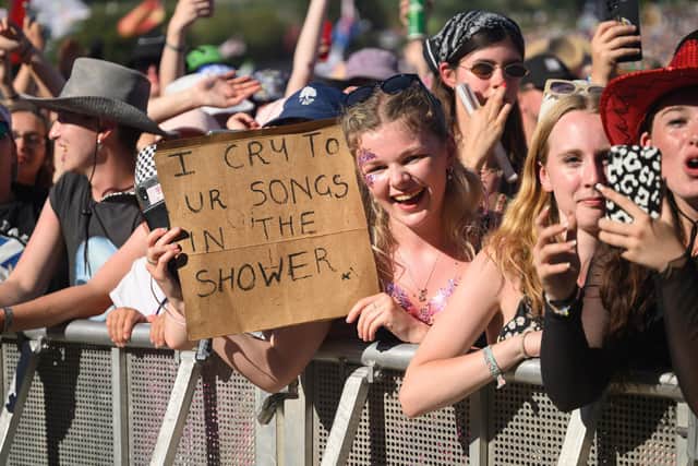 A festival-goer holds up a handwritten sign reading "I Cry To Ur Songs In The Shower" as Lewis Capaldi performs on the Pyramid Stage