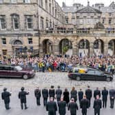 The hearse carrying the coffin of Queen Elizabeth II, draped with the Royal Standard of Scotland, passes the City Chambers on the Royal Mile