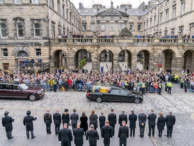 The hearse carrying the coffin of Queen Elizabeth II, draped with the Royal Standard of Scotland, passes the City Chambers on the Royal Mile