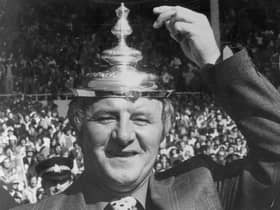 The Doc tips his makeshift hat - the FA Cup final lid - to his exciting Manchester United team after their 1977 Wembley triumph.