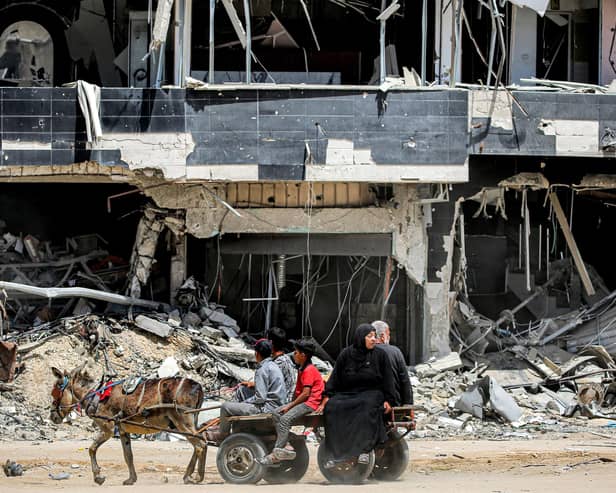 People ride a donkey-drawn cart moving past a destroyed building in Khan Yunis in the southern Gaza Strip. Picture: AFP via Getty Images