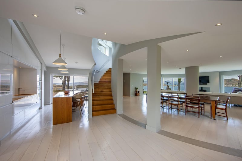 The home’s 3,600sq ft of floorspace includes a glazed vestibule, impressive family area with sweeping staircase, open-plan drawing room with full curved wall of floor-to-ceiling glass, and a kitchen with breakfast bar.