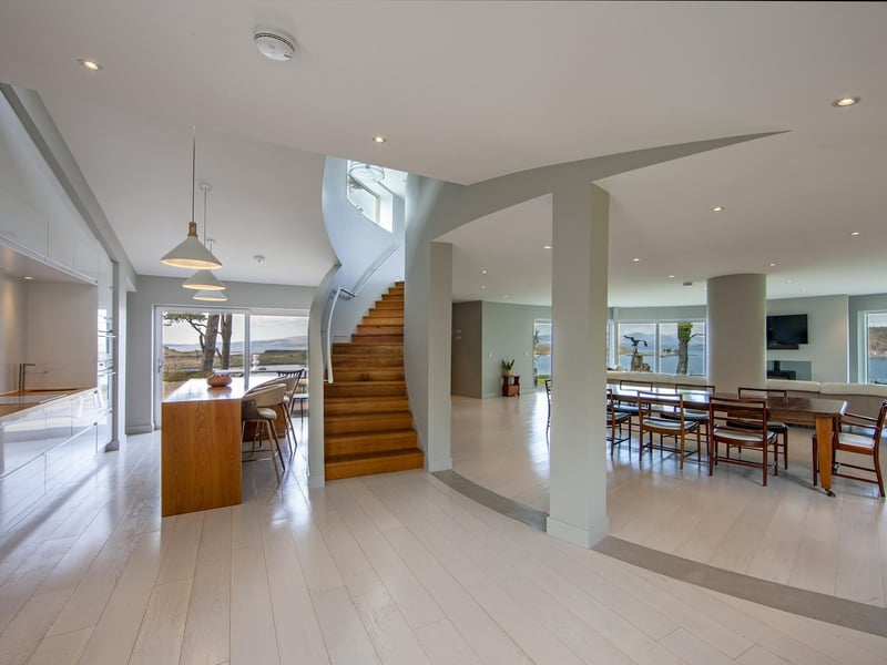 The home’s 3,600sq ft of floorspace includes a glazed vestibule, impressive family area with sweeping staircase, open-plan drawing room with full curved wall of floor-to-ceiling glass, and a kitchen with breakfast bar.