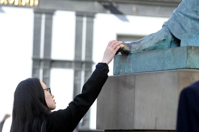 A tourist rubs the toe of the statue to David Hume on the Royal Mile (Picture: Lisa Ferguson)