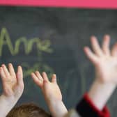 Children waving their hands in a classroom (Photo by Christopher Furlong/Getty Images)