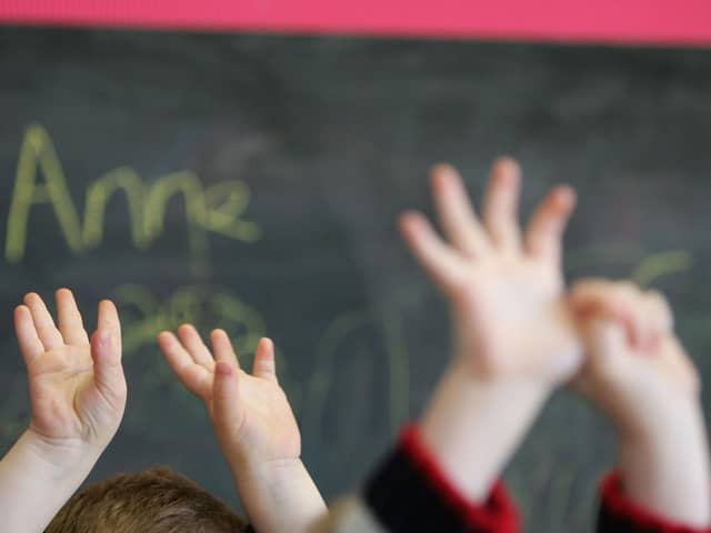 Children waving their hands in a classroom (Photo by Christopher Furlong/Getty Images)