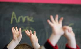 Children waving their hands in a classroom (Photo by Christopher Furlong/Getty Images)