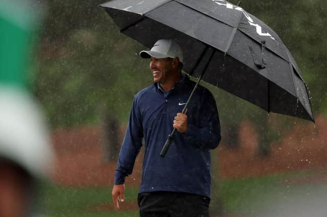 Brooks Koepka shelters under a brolley on a wet day at Augusta National Golf Club. Picture: Patrick Smith/Getty Images.