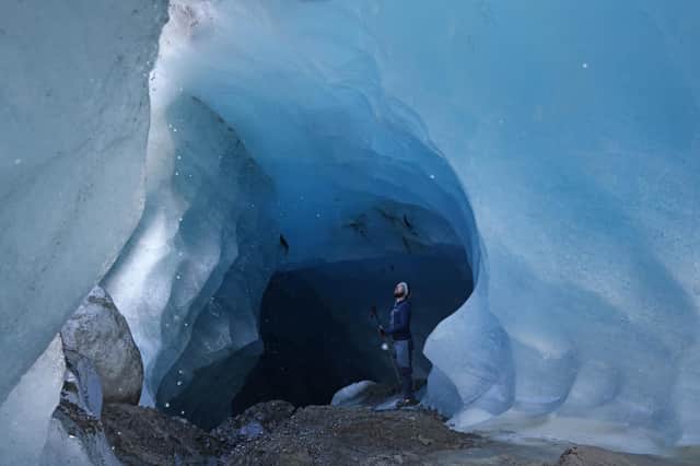 A glaciologist with the Institute for Interdisciplinary Mountain Research of the Austrian Academy of Sciences, stands inside a tunnel of ice formed by rushing meltwater inside the upper plateau of the Gepatschferner glacier (Photo by Sean Gallup/Getty Images)