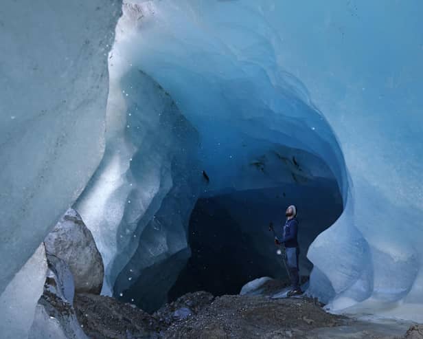 A glaciologist with the Institute for Interdisciplinary Mountain Research of the Austrian Academy of Sciences, stands inside a tunnel of ice formed by rushing meltwater inside the upper plateau of the Gepatschferner glacier (Photo by Sean Gallup/Getty Images)