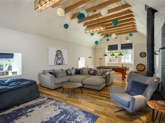 Games room with exposed ceiling beams, solid fuel stove, and built-in dresser / TV cabinet.