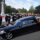 Members of the military salute the hearse carrying the coffin of Queen Elizabeth II, draped with the Royal Standard of Scotland, as it passes the war memorial in Ballater on the journey from Balmoral to Edinburgh (Picture: Andrew Milligan/PA Wire)