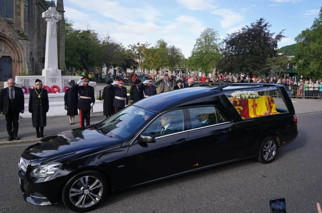 Members of the military salute the hearse carrying the coffin of Queen Elizabeth II, draped with the Royal Standard of Scotland, as it passes the war memorial in Ballater on the journey from Balmoral to Edinburgh (Picture: Andrew Milligan/PA Wire)