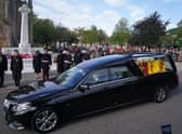 Members of the military salute the hearse carrying the coffin of Queen Elizabeth II, draped with the Royal Standard of Scotland, as it passes the war memorial in Ballater on the journey from Balmoral to Edinburgh (Picture: Andrew Milligan/PA Wire)