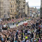The hearse carrying the coffin of Queen Elizabeth II, draped with the Royal Standard of Scotland, passes down the Royal Mile