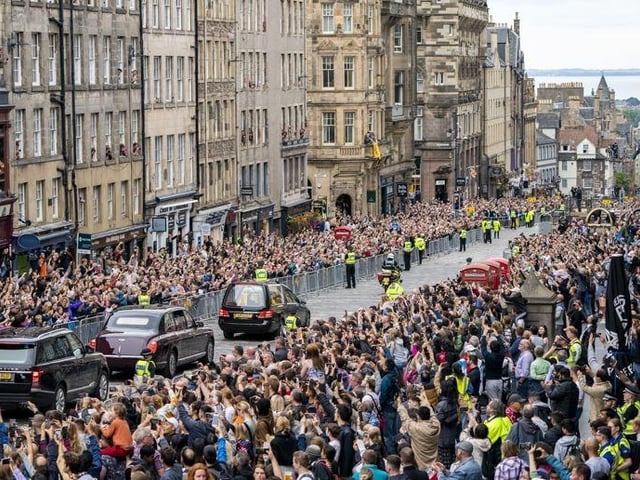 The hearse carrying the coffin of Queen Elizabeth II, draped with the Royal Standard of Scotland, passes down the Royal Mile