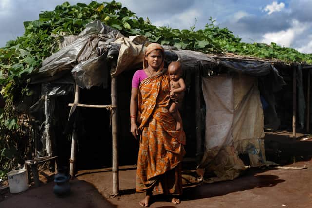 A woman and baby outside her home in the Bangladeshi capital Dhaka. She joined the swelling ranks of Bangladeshi 'climate refugees' after a cyclone wrecked her home and killed more than 3,500 people (Picture: Munir Uz Zaman/AFP via Getty Images)