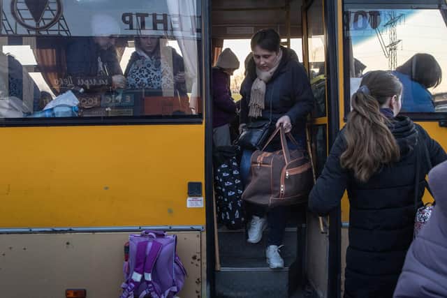 People collect their belongings as they get off a bus that arrived with a large convoy of cars and buses at an evacuation point, carrying hundreds of people from Ukraine. Photo by Chris McGrath/Getty